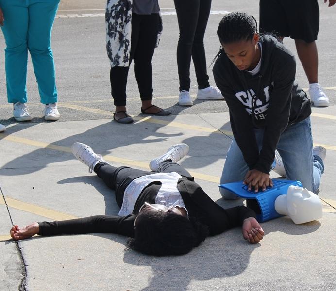 1-2-3: Medical Academy instructor Dr. Alfredo Landron took his class to the back parking lot for a CPR session. Here Jasmine Simmonds practices with victim Faith Dormestoire.
