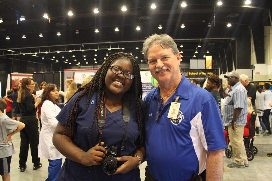 TAKING THE MESSAGE TO THE MASSES: Medical Academy freshman and journalist Brianna Luberisse joined Principal Jack Myszkowski as Inlet Grove staff provided information to students and their families during the annual Showcase of Schools Oct. 18.
