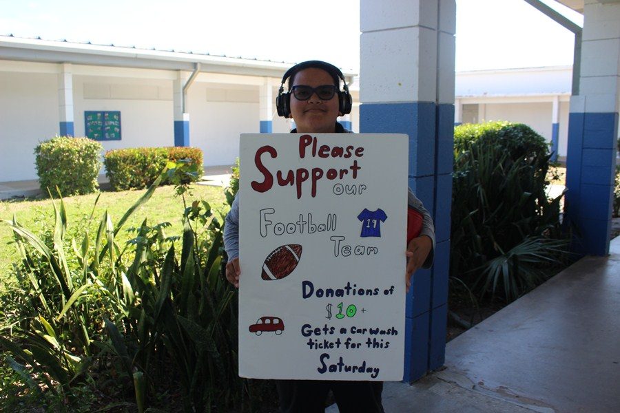 SUPPORT WANTED:
 Alyssa Tenorio, a fellow Cane  stands with poster in support of the Inlet Grove football team.