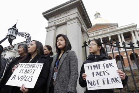 Jessica Wong, of Fall River, Mass., front left, Jenny Chiang, of Medford, Mass., center, and Sheila Vo, of Boston, from the states Asian American Commission, stand together during a protest, Thursday, March 12, 2020, on the steps of the Statehouse in Boston. Asian American leaders in Massachusetts condemned what they say is racism, fear-mongering and misinformation aimed at Asian communities amid the widening coronavirus pandemic that originated in China.