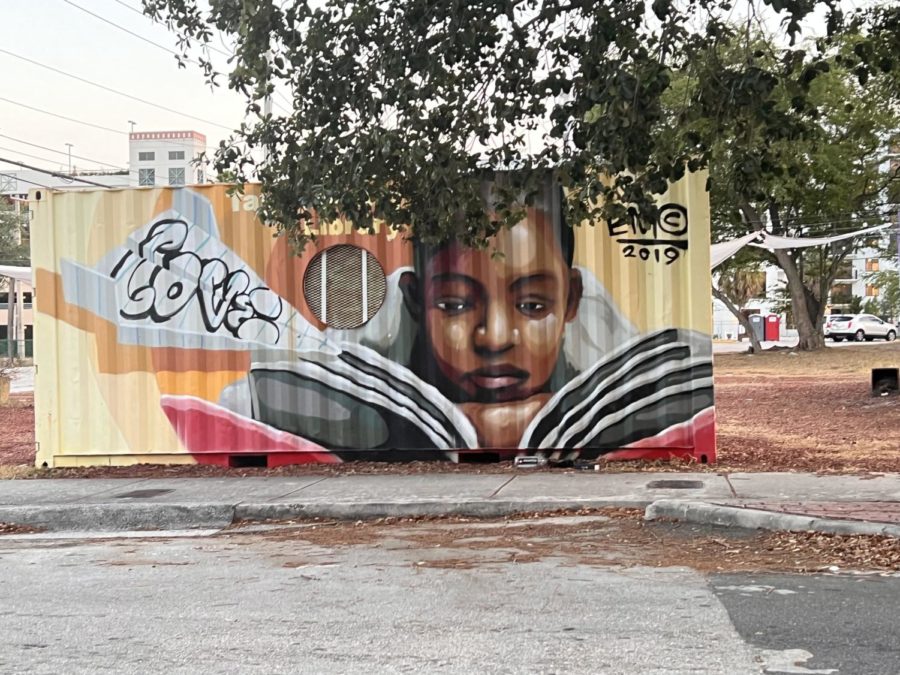 EDUCATED: A black young woman reading a book is displayed on a shipping container flipped to function as a mini library.