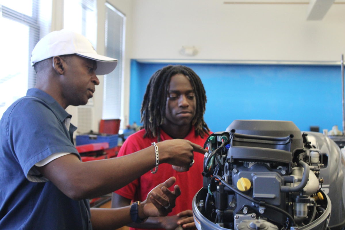OVERVIEW: Marine Academy instructor Mr.Burt is  shown above teaching student Chance Williams on how to construct the motor of a boat 