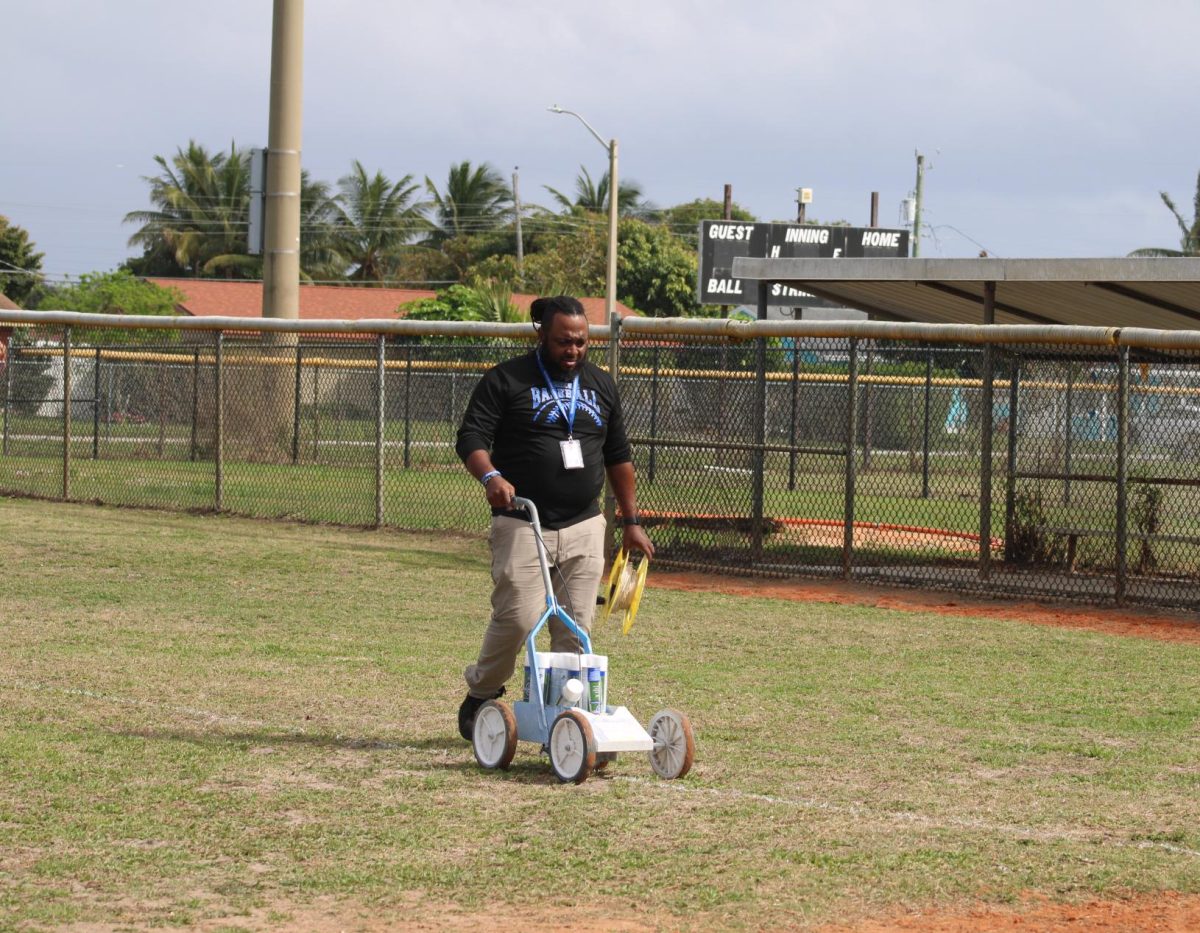 GET READY: Coach Jones and a few students prepare the baseball field for their first home game March 4. 