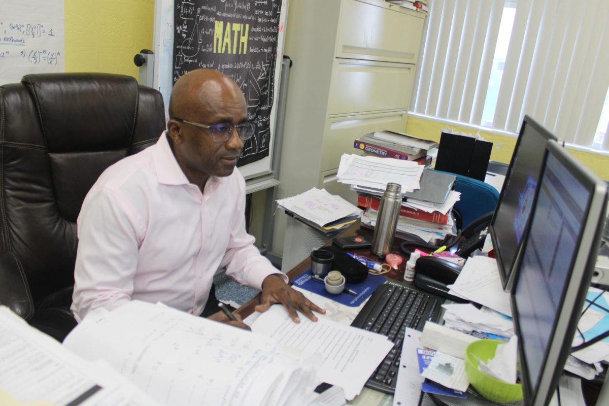WORK MODE: Mr. Micheal takes a moment behind his desk to prepare for class and organize lessons.