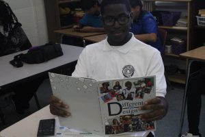 REFLECTING: A student flips through the yearbook, revisiting memories from the school year. (Camera settings: 5000 iso, F/10 aperture, 1/200 shutter speed.)
